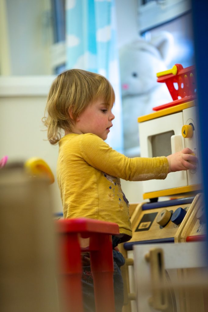 a child playing with a toy kitchen in nursery