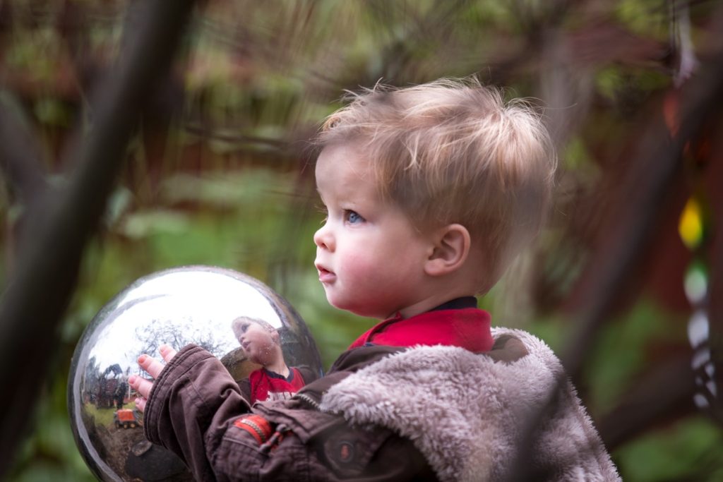 a close up of a child outside touching a reflective shiny object