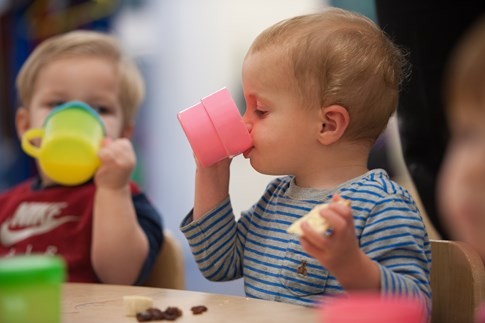 two young children drinking from beakers at a table at little faces nursery in Waterlooville